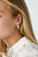 Goldener Ohrstecker in Tropfenform am Ohr einer blonden Frau