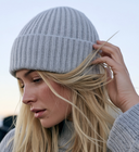 Blonde Frau mit hellgrauer Strickmütze und Strickpullover